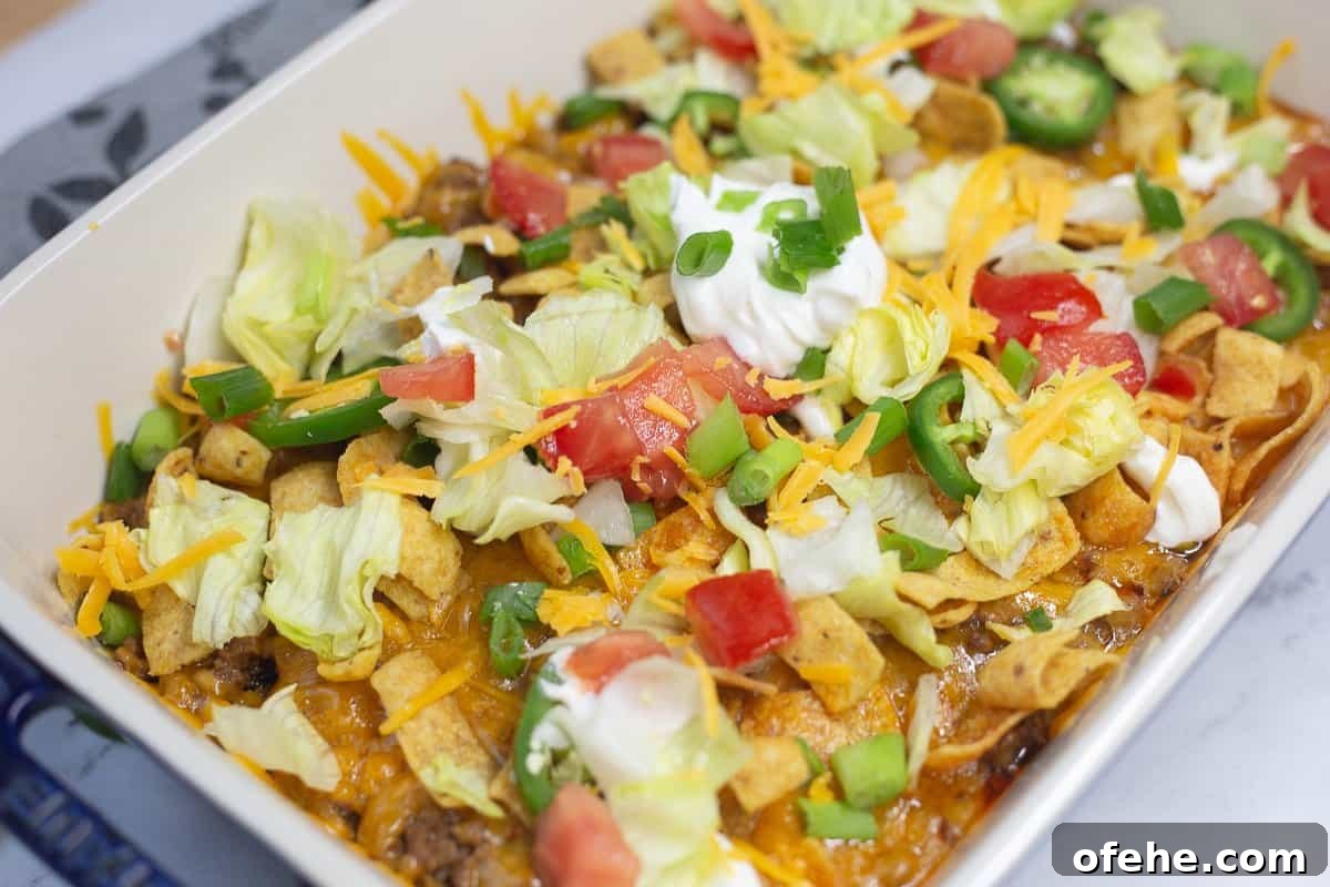 Crunchy Frito Taco Casserole with Melted Cheese and Beef 7 Walking Taco Casserole with shredded lettuce, tomatoes, sour cream and cheese.