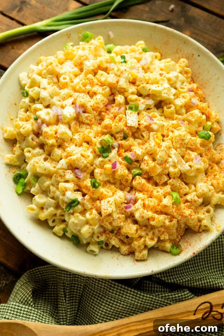 Deviled Egg Pasta Salad for Summer Gatherings 7 a photo of a deviled egg pasta salad topped with green onions and diced red onions