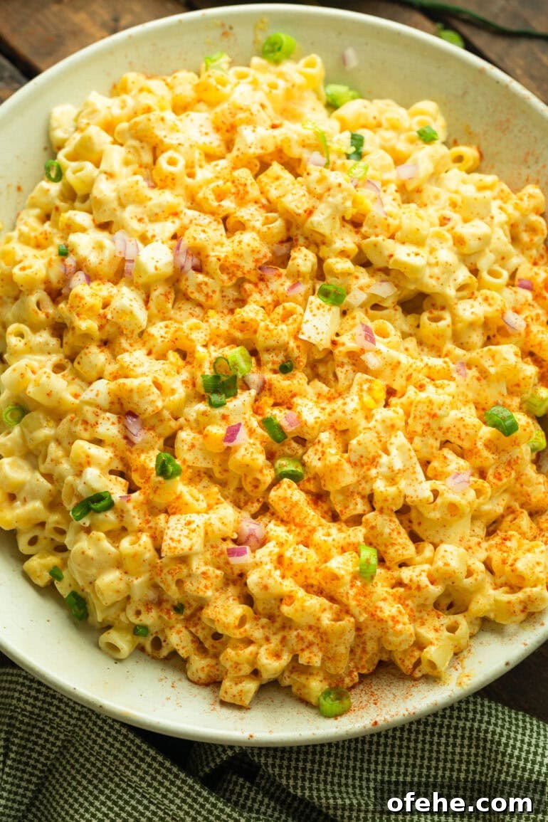 Deviled Egg Pasta Salad for Summer Gatherings 8 a photo of a creamy deviled egg pasta salad topped with diced green onions and red onions