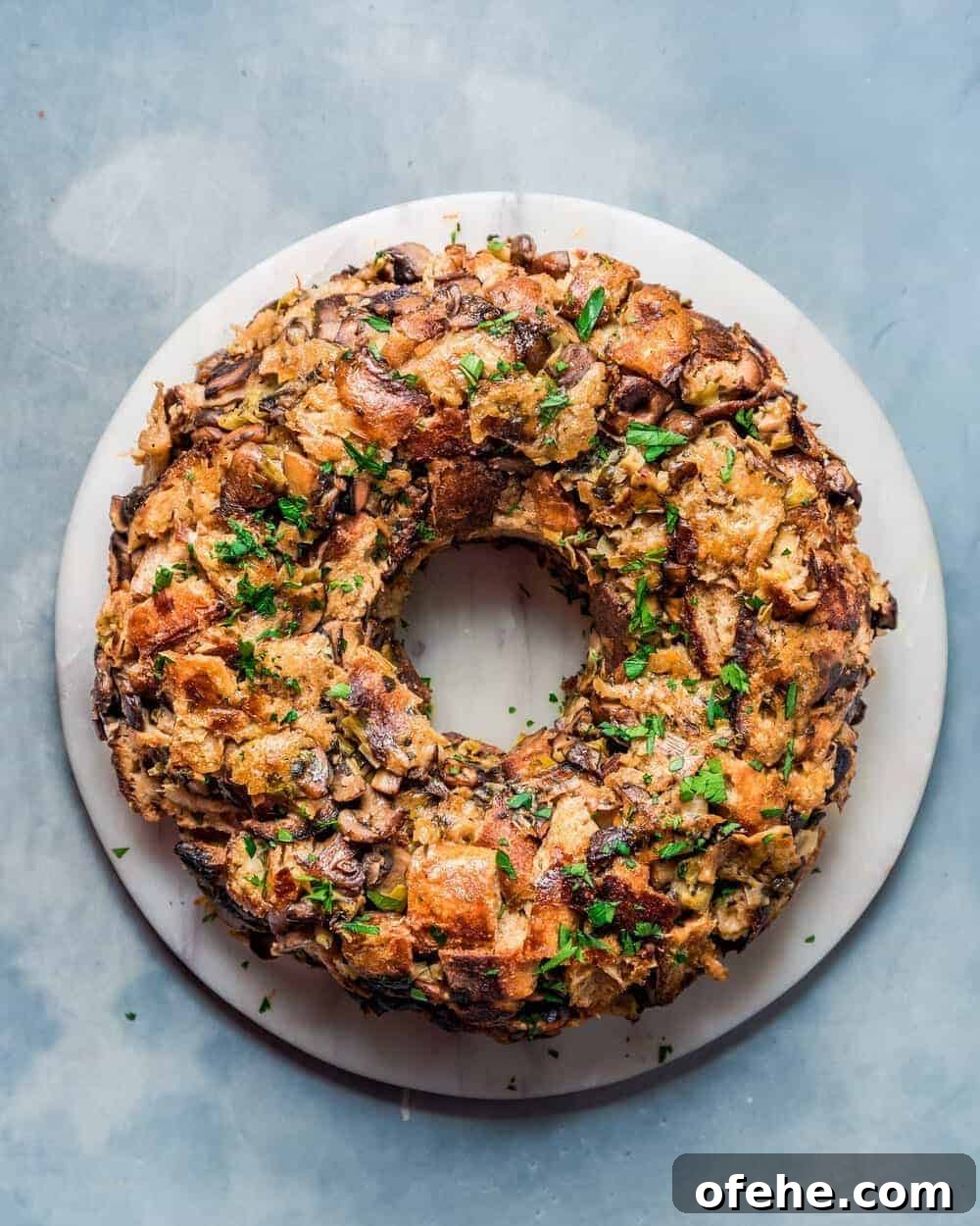 Overhead view of vegan mushroom stuffing wreath on a round marble serving board.
