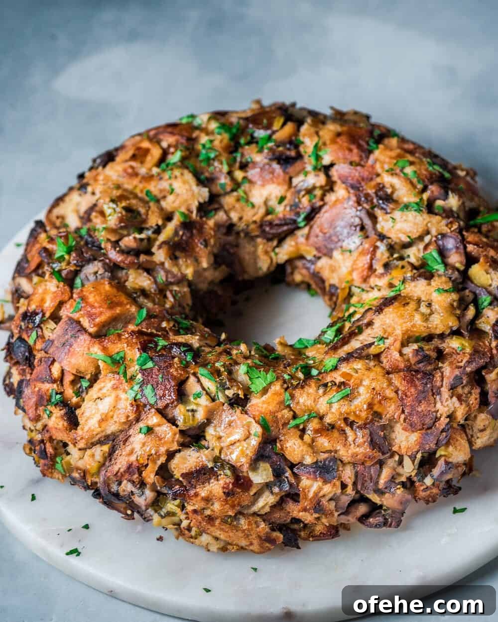 Side view of vegan mushroom stuffing wreath on a round marble serving board.