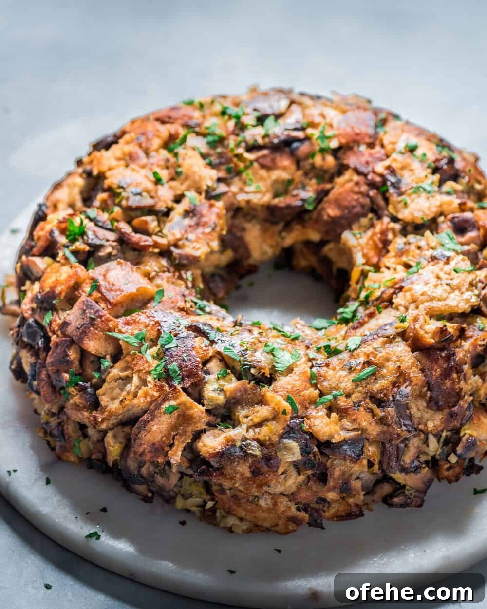 Side view of backlit vegan mushroom stuffing wreath on a round marble serving board.