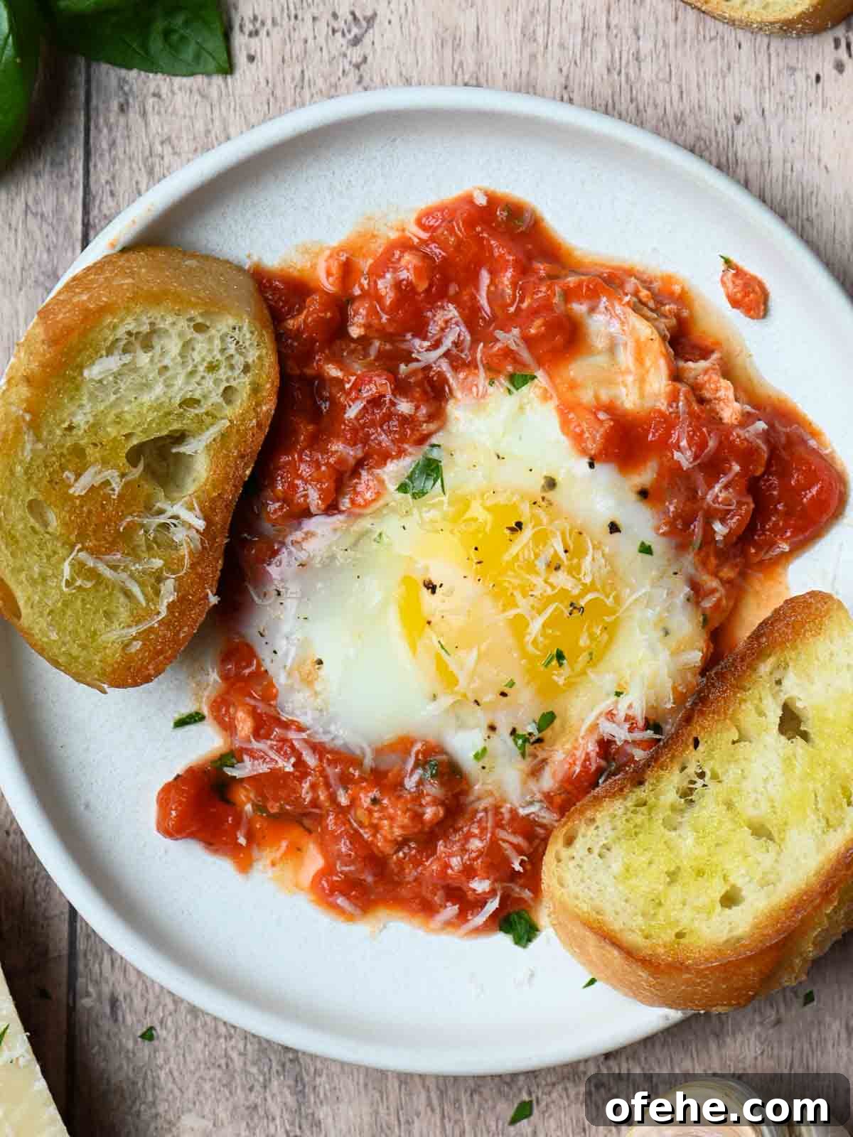 Poached Eggs in Spicy Tomato Sauce (Eggs in Purgatory) 11 Overview of eggs, sauce and bread on a white plate.