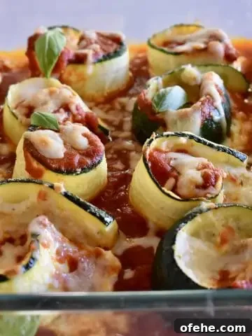 Zucchini Ricotta Roll Ups in a glass pan with basil leaves on top.
