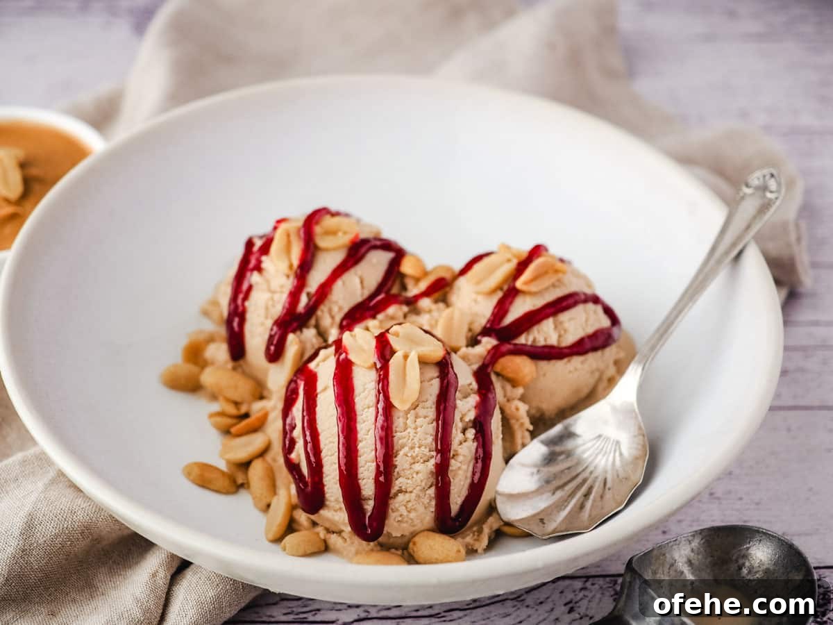 Creamy Peanut Butter Ice Cream Recipe for Homemade Treat 8 Scoops of peanut butter ice cream drizzled with raspberry jam in a bowl.