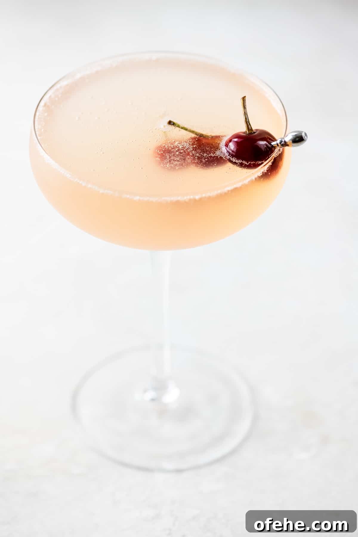 Sour Cherry French 75 Cocktail for Seasonal Entertaining 2 French 75 Sour Cherry Cocktail in a coupe glass garnished with homemade maraschino cherries