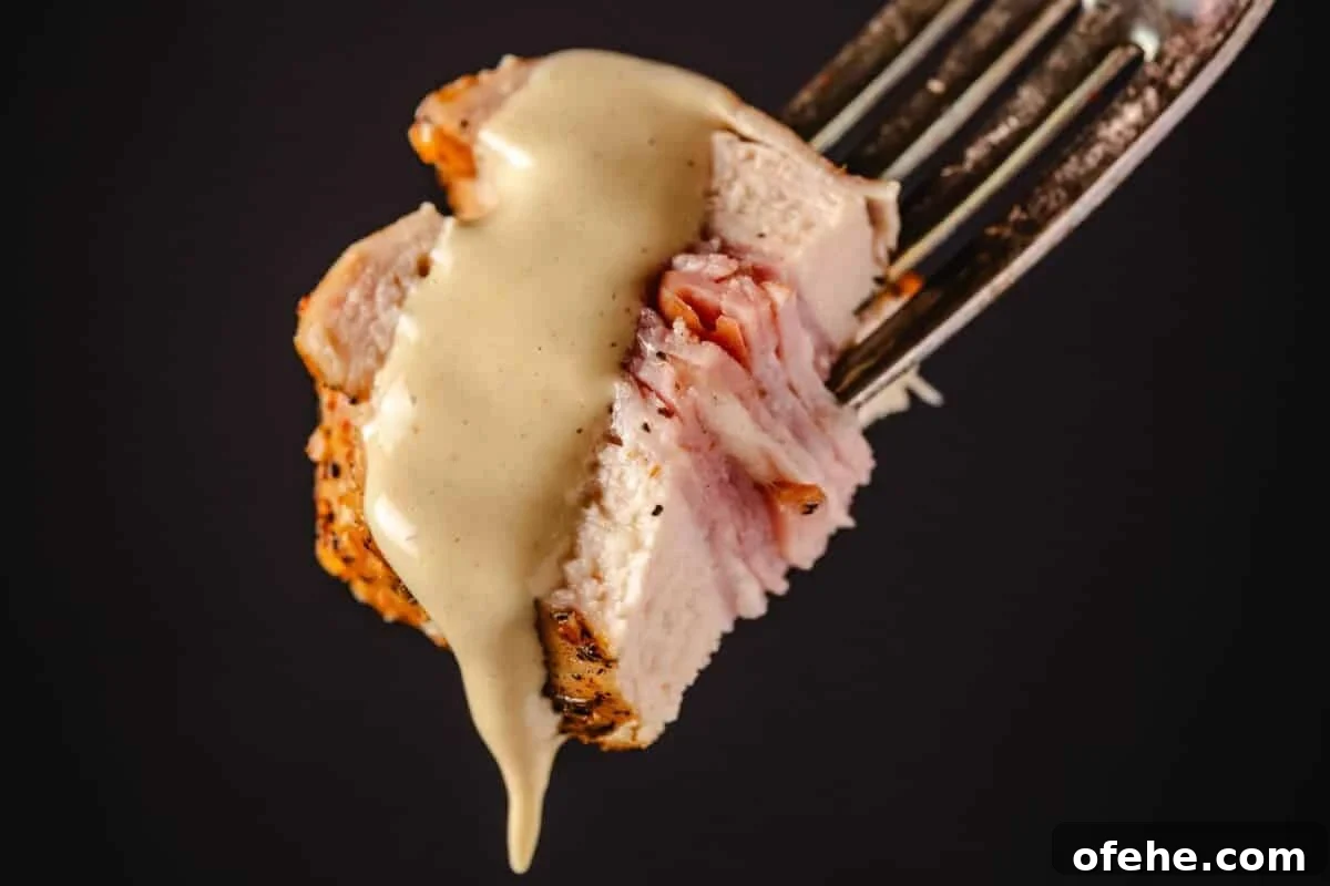 Crispy Grilled Chicken Cordon Bleu Recipe with Ham & Melty Cheese 8 Chicken cordon bleu bit drizzled with dijon sauce on fork.