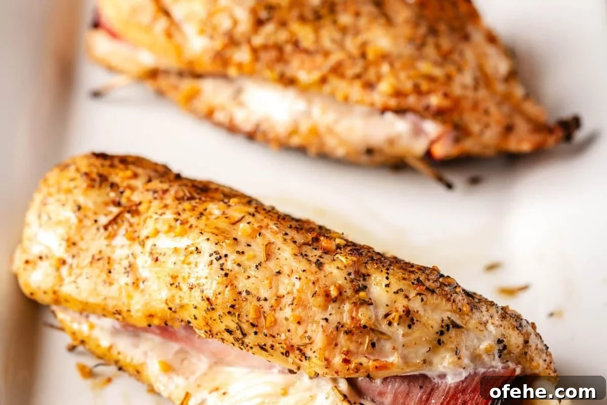 Crispy Grilled Chicken Cordon Bleu Recipe with Ham & Melty Cheese 6 Two grilled chicken breasts on a white plate.