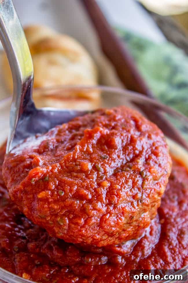 a ladle lifting pizza sauce from a glass bowl.