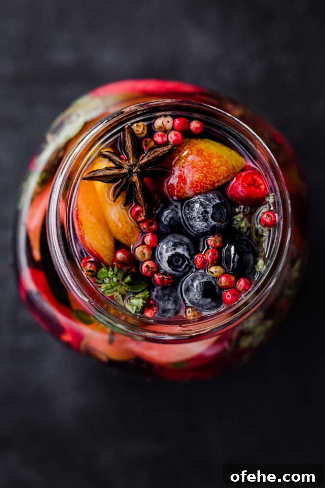 Quick Pickled Fruit: Perfect Brine Ratio for Every Batch 6 Blueberries, peaches and other fruit pickled in a jar with start anise, pink peppercorns, chili, thyme, and pickling brine, overhead shot.