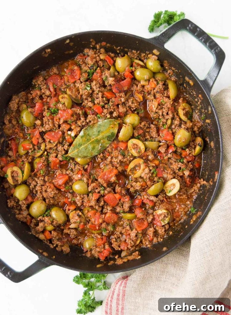 Authentic Brazilian Picadillo (Picadinho) Recipe for Dinner 3 Brazilian Picadillo in a black braising pan sits on top of a red and beige striped towel