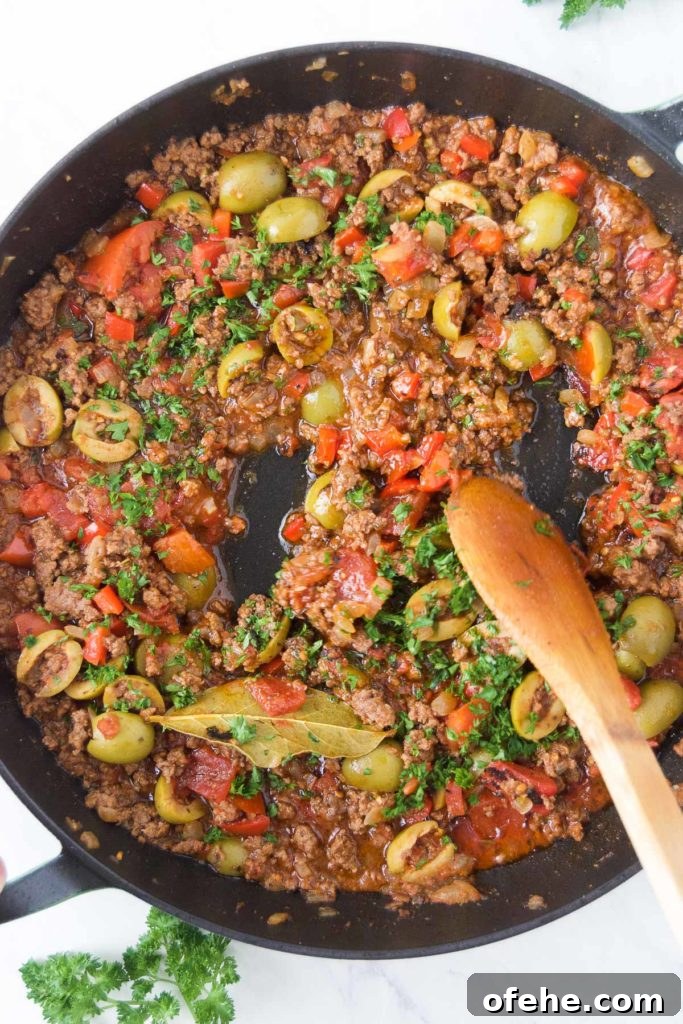 Authentic Brazilian Picadillo (Picadinho) Recipe for Dinner 10 A wooden spoon stirs fresh parsley into a picadillo in a black skillet