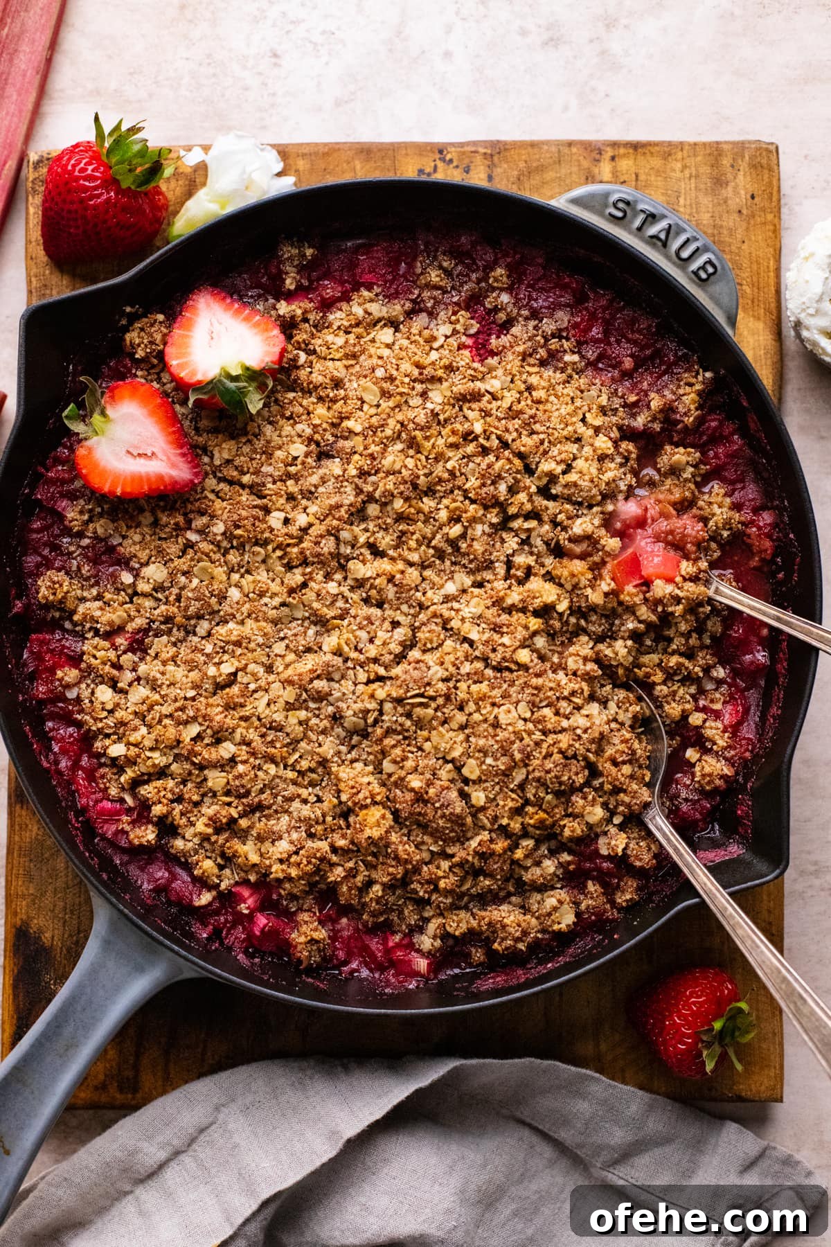 Gluten-Free Strawberry Rhubarb Crisp Recipe for Summer Dessert 2 skillet pan with gluten free strawberry rhubarb crisp in it on brown wooden board.