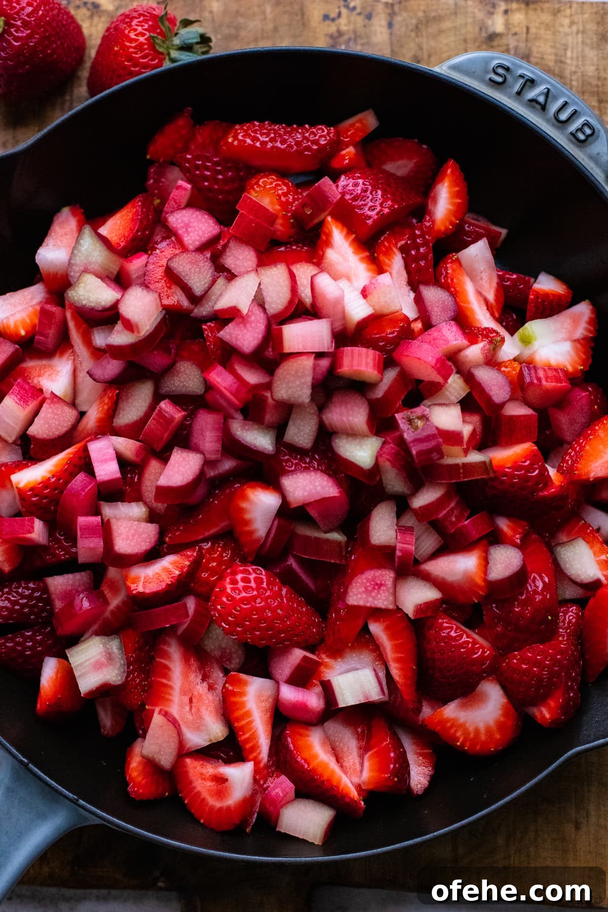 Gluten-Free Strawberry Rhubarb Crisp Recipe for Summer Dessert 6 pieces of strawberries and rhubarb in a skillet pan.