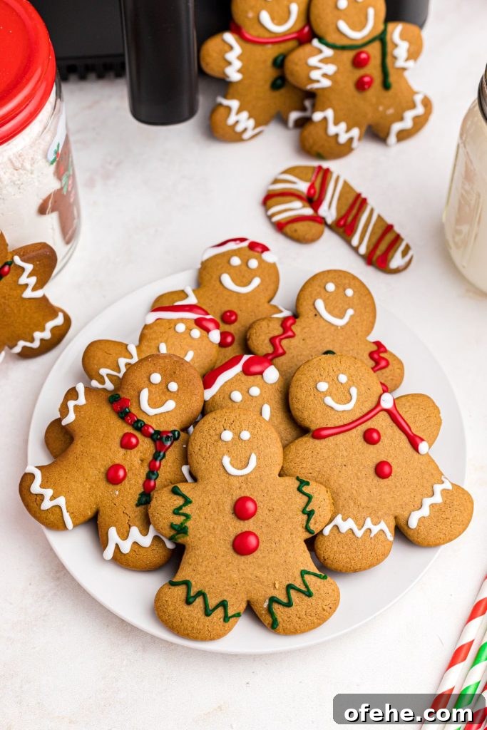 Chewy Air Fryer Gingerbread Cookies Recipe 2 Golden gingerbread men on a white plate in front of an air fryer