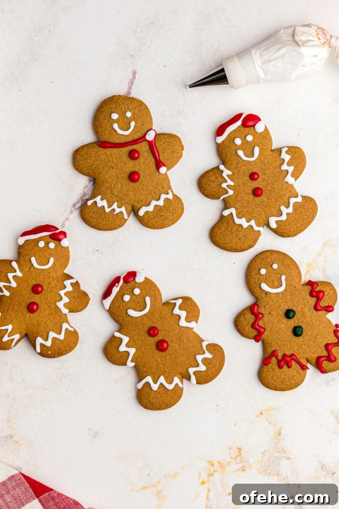 Chewy Air Fryer Gingerbread Cookies Recipe 11 Golden gingerbread men cookies on a marble table being frosted
