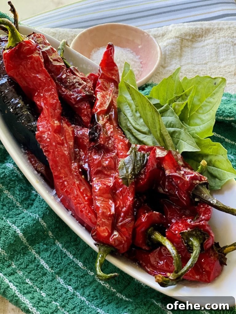 Crispy Sautéed Italian Sweet Peppers with Garlic & Herbs 11 Finished Fried Italian Sweet Peppers with basil garnish on Platter with small bowl of sea salt in background.