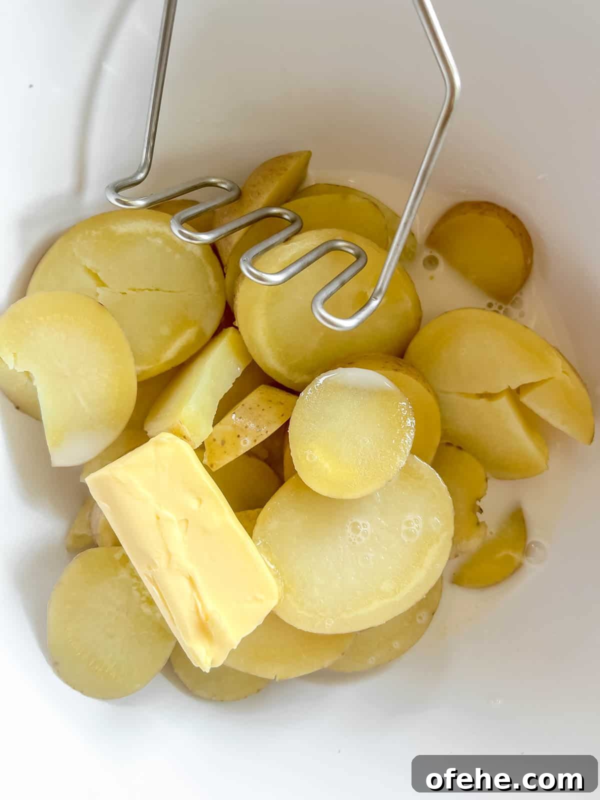 Gluten-Free Potato Pancakes with Optional Whole30 Version 8 The boiled potatoes in a bowl with butter and almond milk ready to be mashed.