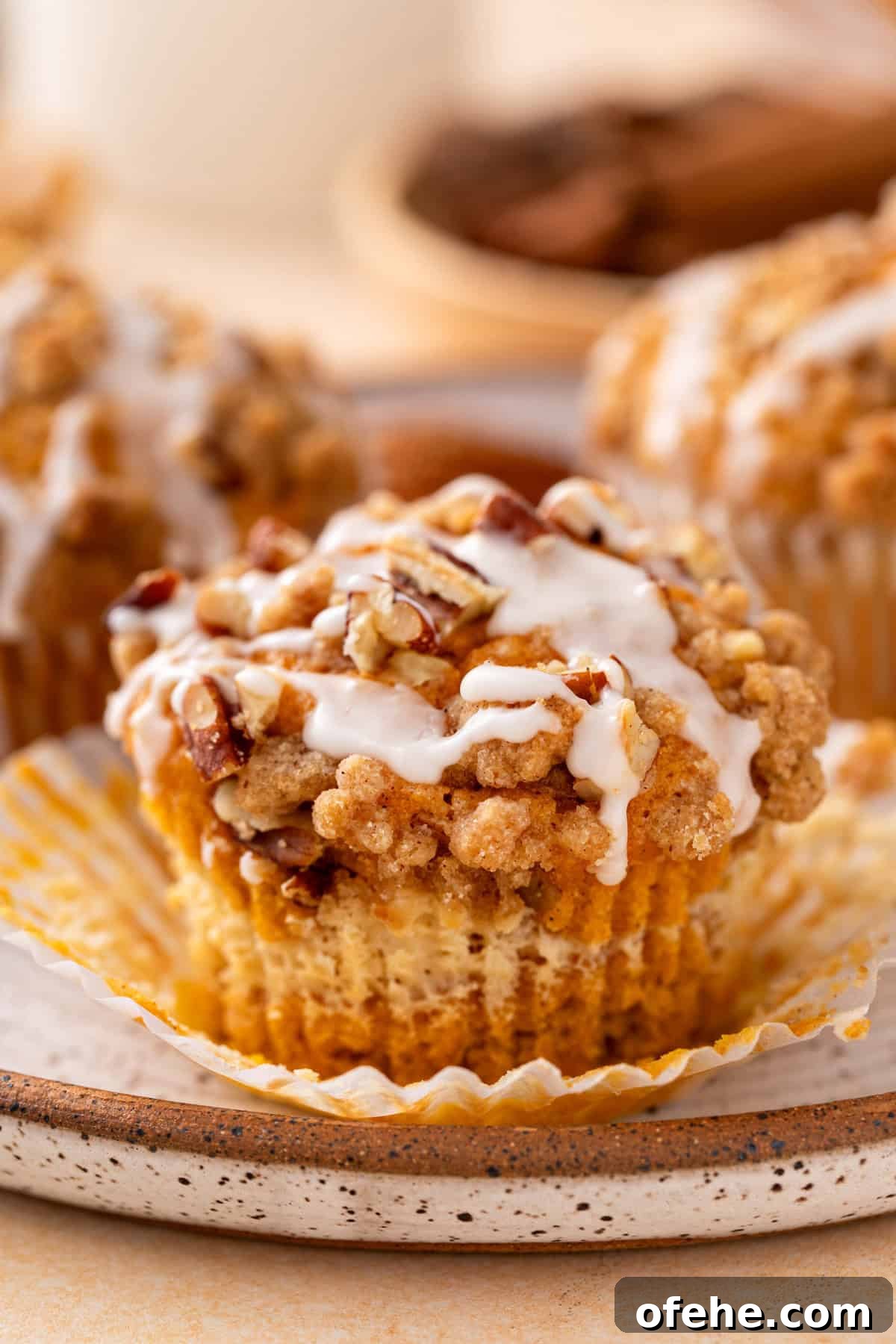 Pumpkin Muffins with Cream Cheese Swirl: Moist Fall Recipe 2 Pumpkin cream cheese muffin on a plate. The muffin's wrapper is unwrapped.