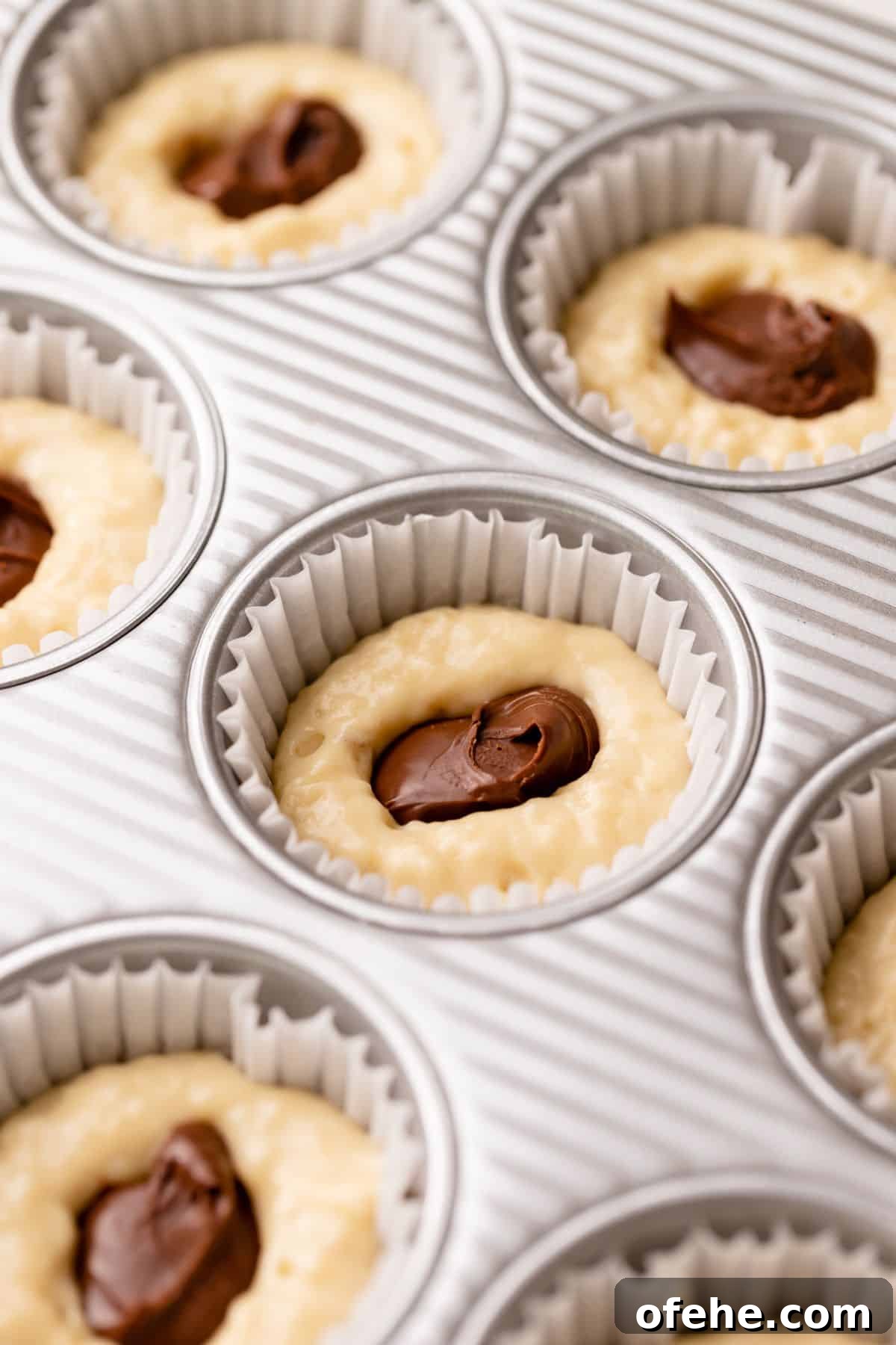 Chocolate Hazelnut Banana Muffins — Moist & Gooey Recipe 8 Muffins being stuffed with scoops of nutella spread.