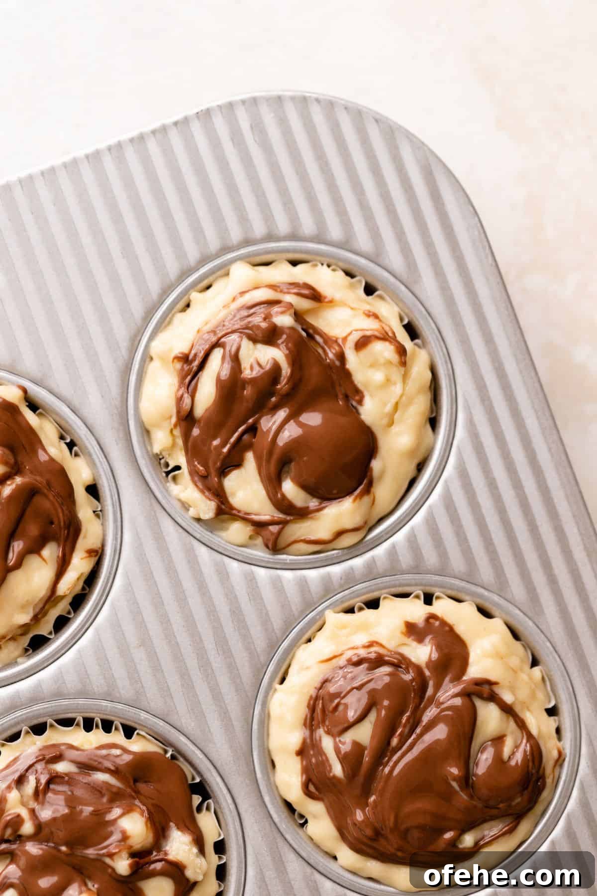 Chocolate Hazelnut Banana Muffins — Moist & Gooey Recipe 9 Nutella swirled on the tops of the muffin batter.