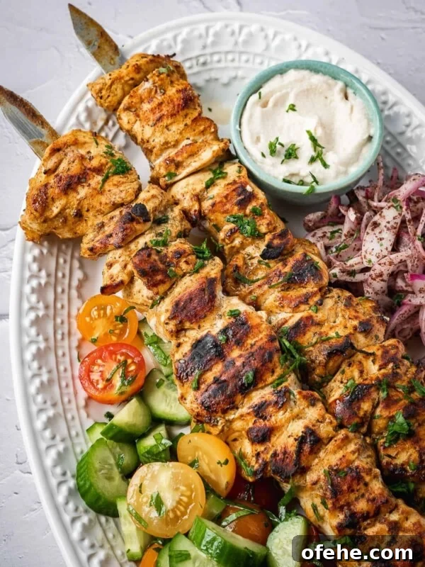 Persian Saffron Joojeh Kabob Recipe — Grilled Chicken Kabab 11 A plate of shish tawook skewers with a side salad, pickled sumac onions and garlic sauce.