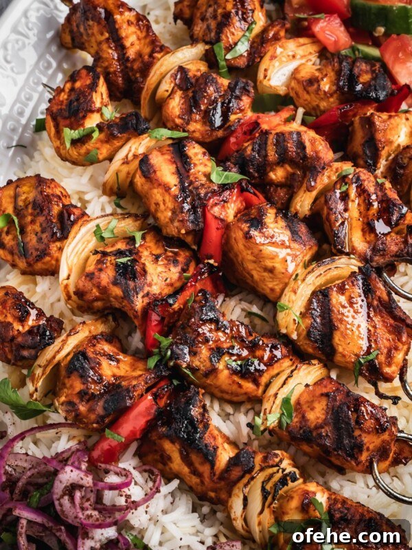 Persian Saffron Joojeh Kabob Recipe — Grilled Chicken Kabab 13 A platter with rice, chopped salad, sumac onions and harissa chicken skewers.
