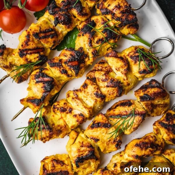 Persian Saffron Joojeh Kabob Recipe — Grilled Chicken Kabab 15 Grilled Joojeh Kabob chicken skewers with a golden char served on a white platter, garnished with fresh dill, cherry tomatoes.