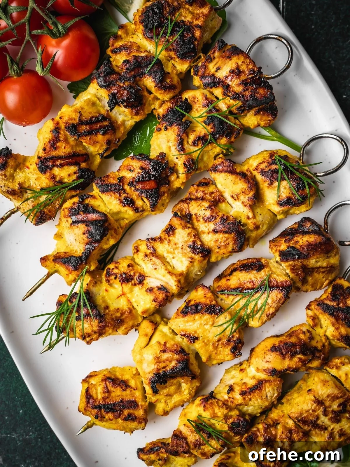Persian Saffron Joojeh Kabob Recipe — Grilled Chicken Kabab 10 Grilled Joojeh Kabob chicken skewers with a golden char served on a white platter, garnished with fresh dill, cherry tomatoes.