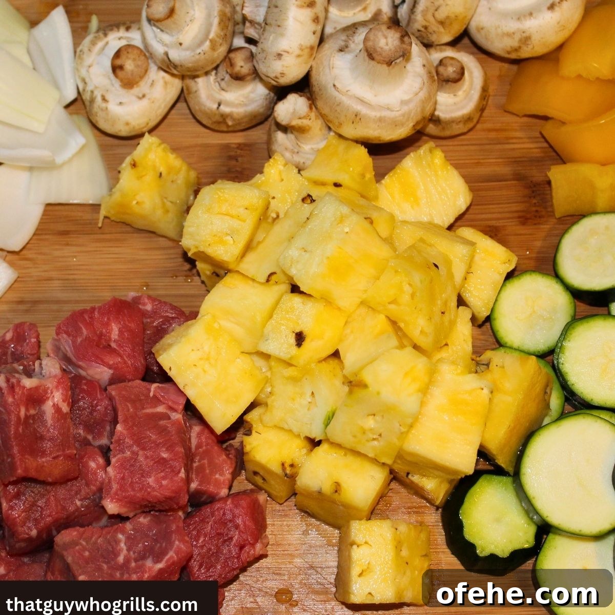 Juicy Grilled Steak Kabobs with Garlic Herb Marinade 3 Cubed Steak on a cutting board with cut pineapple, sliced zucchini, mushrooms, yellow pepper, and white onions