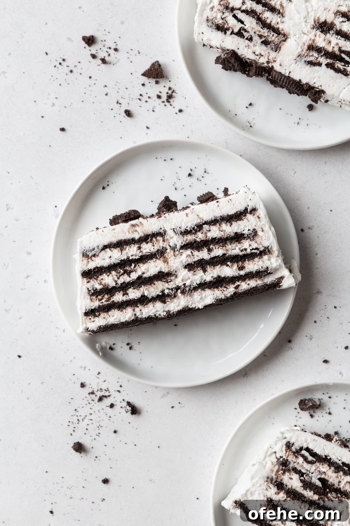 No-Bake Icebox Cake Recipe for Creamy Layered Dessert 2 Three slices of icebox cake on white plates on a light grey surface.