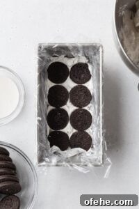 No-Bake Icebox Cake Recipe for Creamy Layered Dessert 5 Chocolate cookies in a loaf pan with cream underneath.