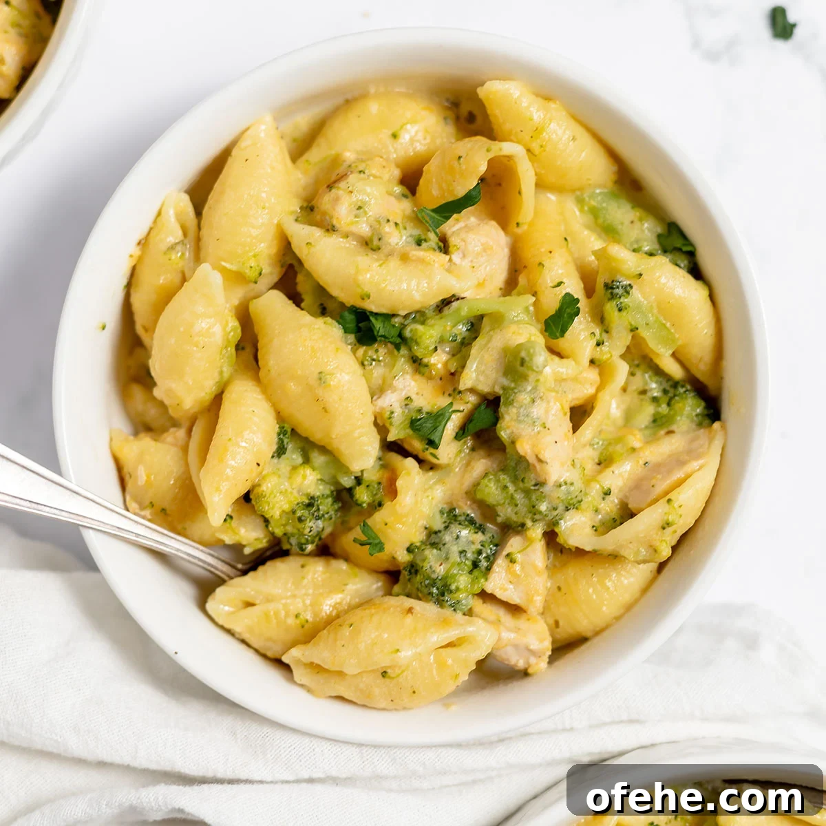 Serving of chicken broccoli pasta in a white bowl.