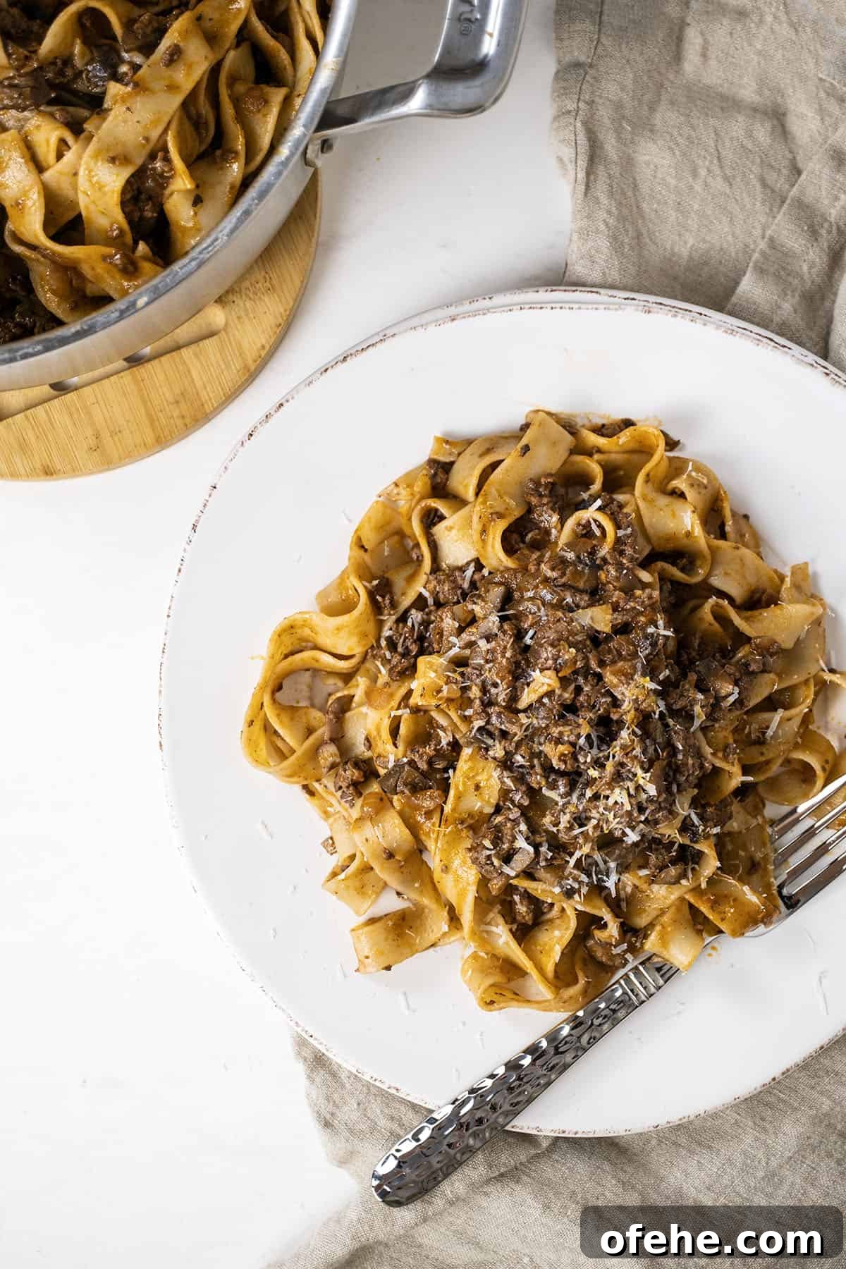 20-Minute Lamb Ragu with Pappardelle: Rustic Weeknight Pasta Recipe 12 Lamb ragu over pappardelle on a small plate with pan with pasta next to it.