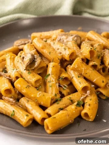 Creamy garlic mushroom pasta on a plate garnished with parmesan.
