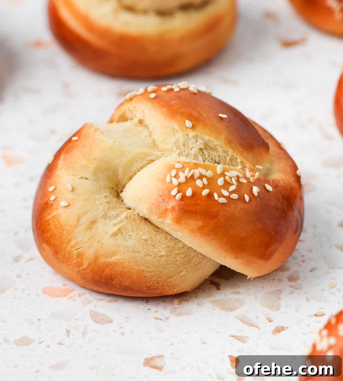 Soft and Fluffy Challah Dinner Rolls: Perfect for Any Meal 11 Close up on one roll on a white and pink surface.