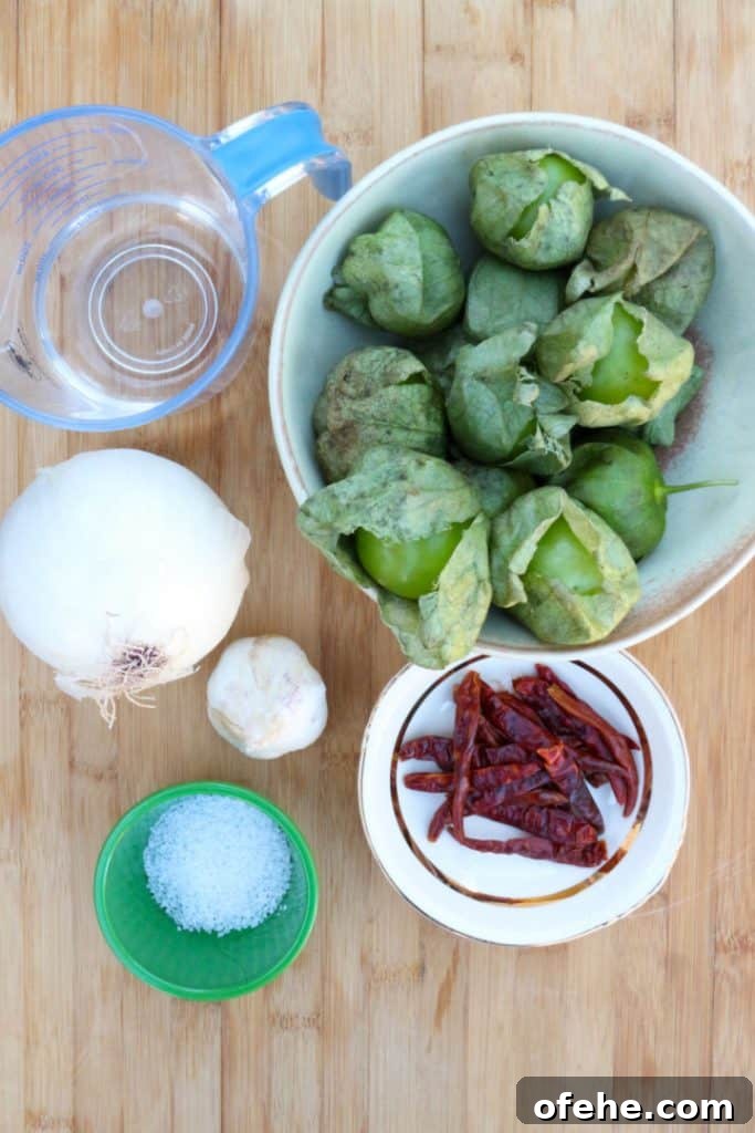 Roasted Tomatillo Salsa with Chile de Arbol Recipe 3 Tomatillos in a bowl, water in a measuring cup, chiles de arbol, salt, garlic and onion.