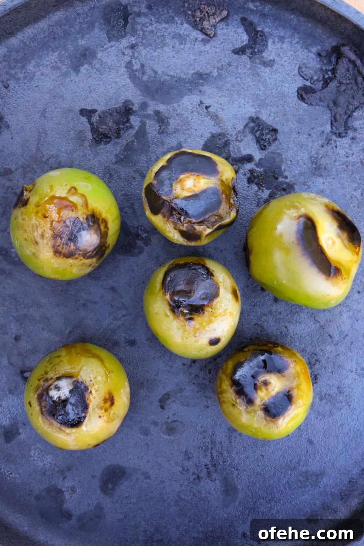 Roasted Tomatillo Salsa with Chile de Arbol Recipe 4 Charred tomatillos on a cast-iron comal.