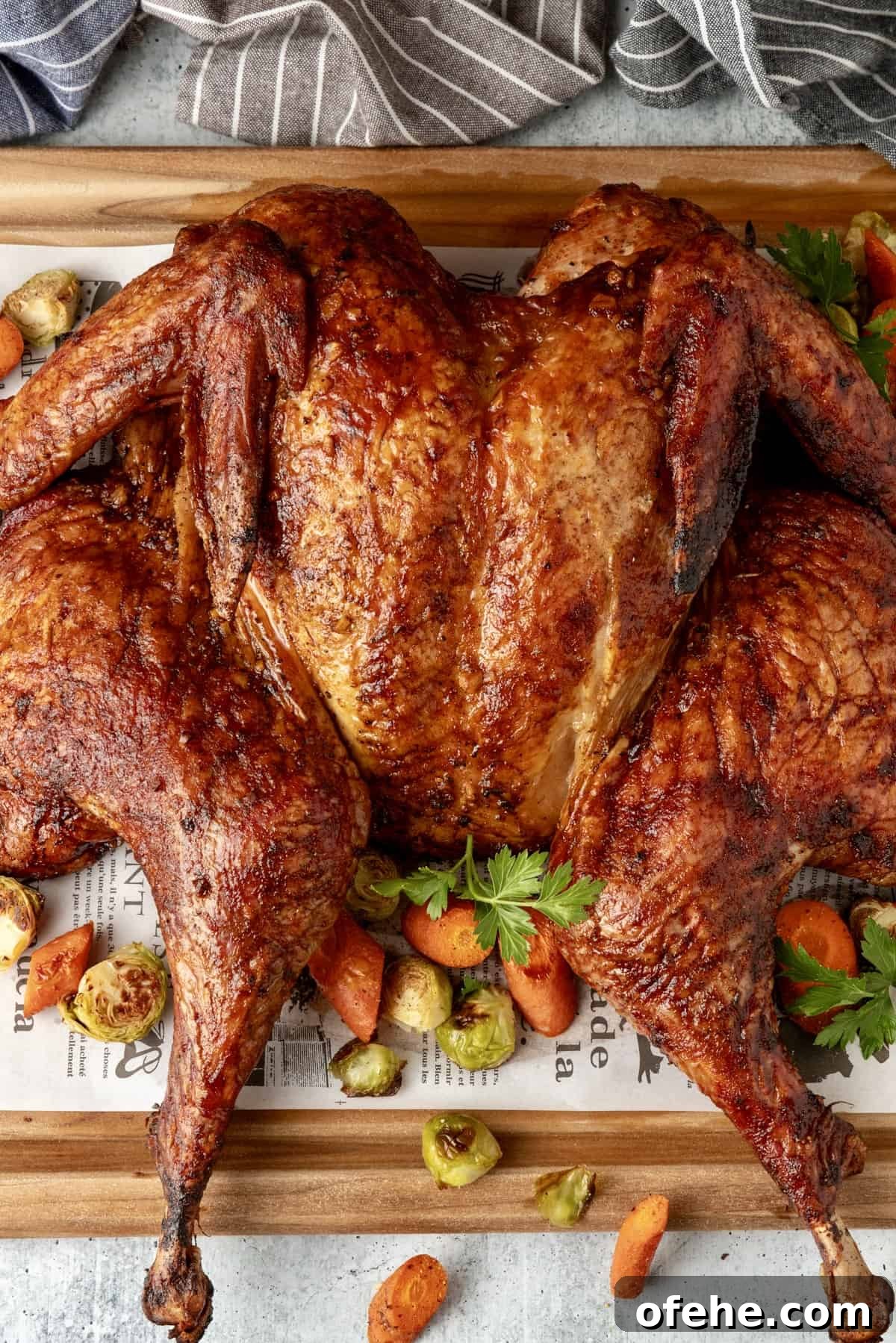 Sriracha-Glazed Smoked Spatchcock Turkey Recipe 2 Smoked spatchcock turkey on cutting board with vegetables surrounding bird.