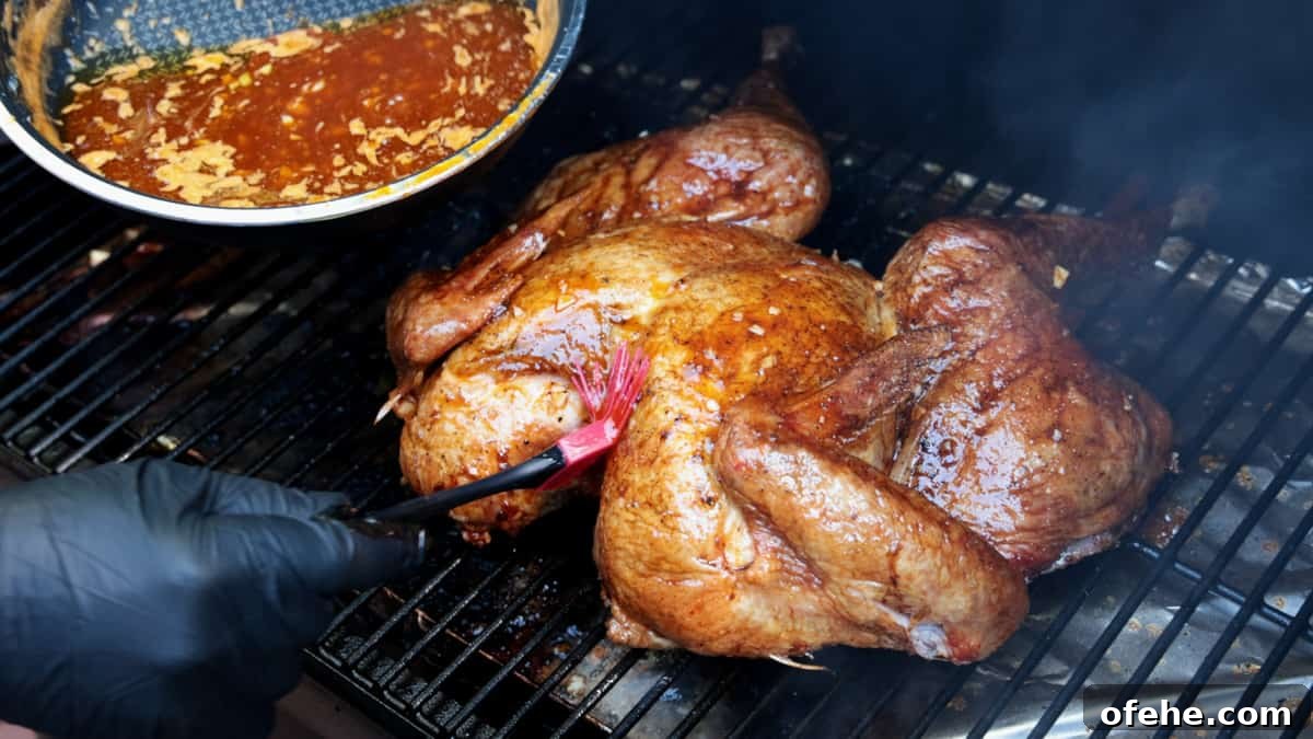 Sriracha-Glazed Smoked Spatchcock Turkey Recipe 8 Applying sriracha glaze to turkey with red brush while turkey is on grill rack of smoker.