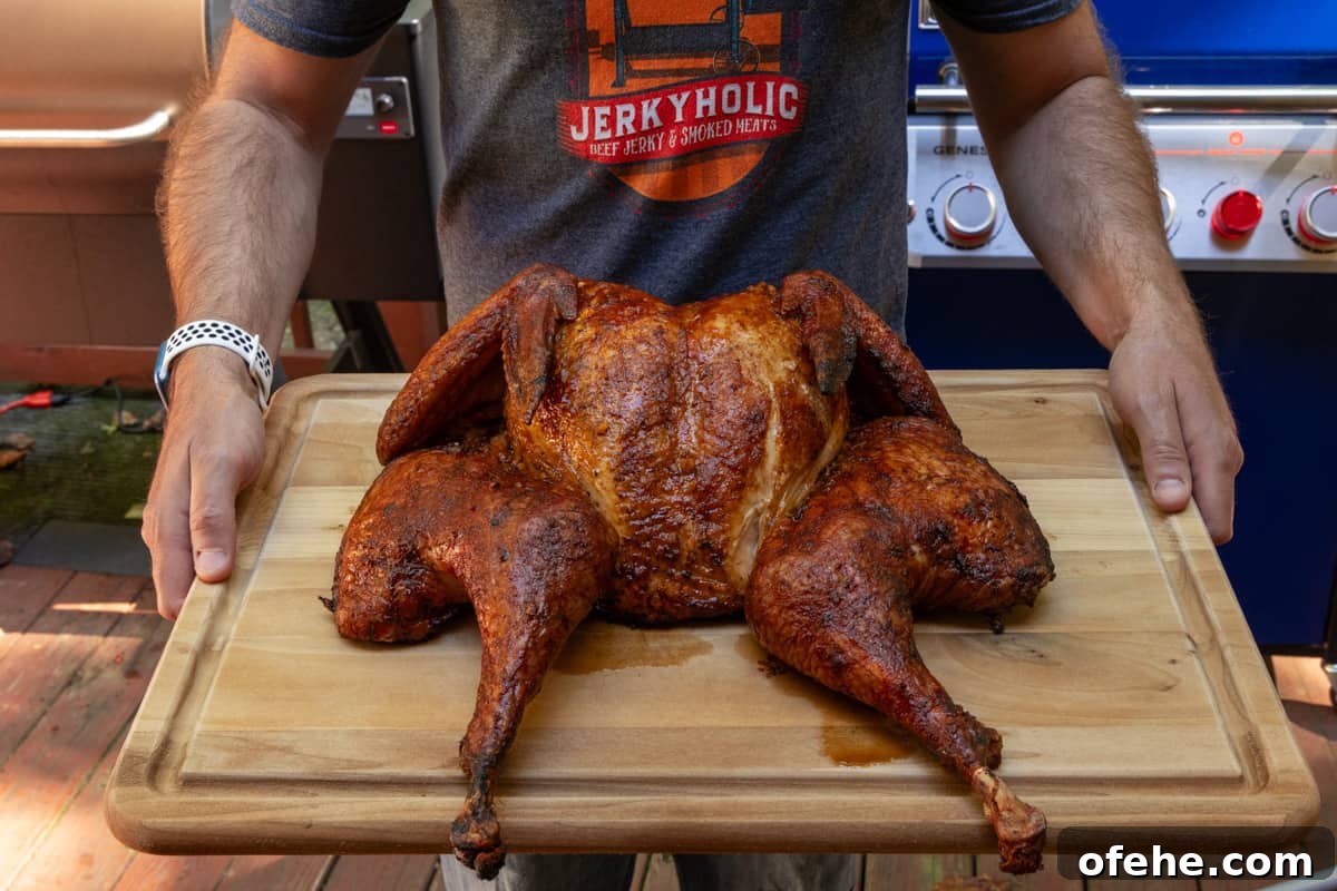 Sriracha-Glazed Smoked Spatchcock Turkey Recipe 9 Spatchcock turkey on cutting board after cooking being held by man wearing a jerkyholic t shirt.