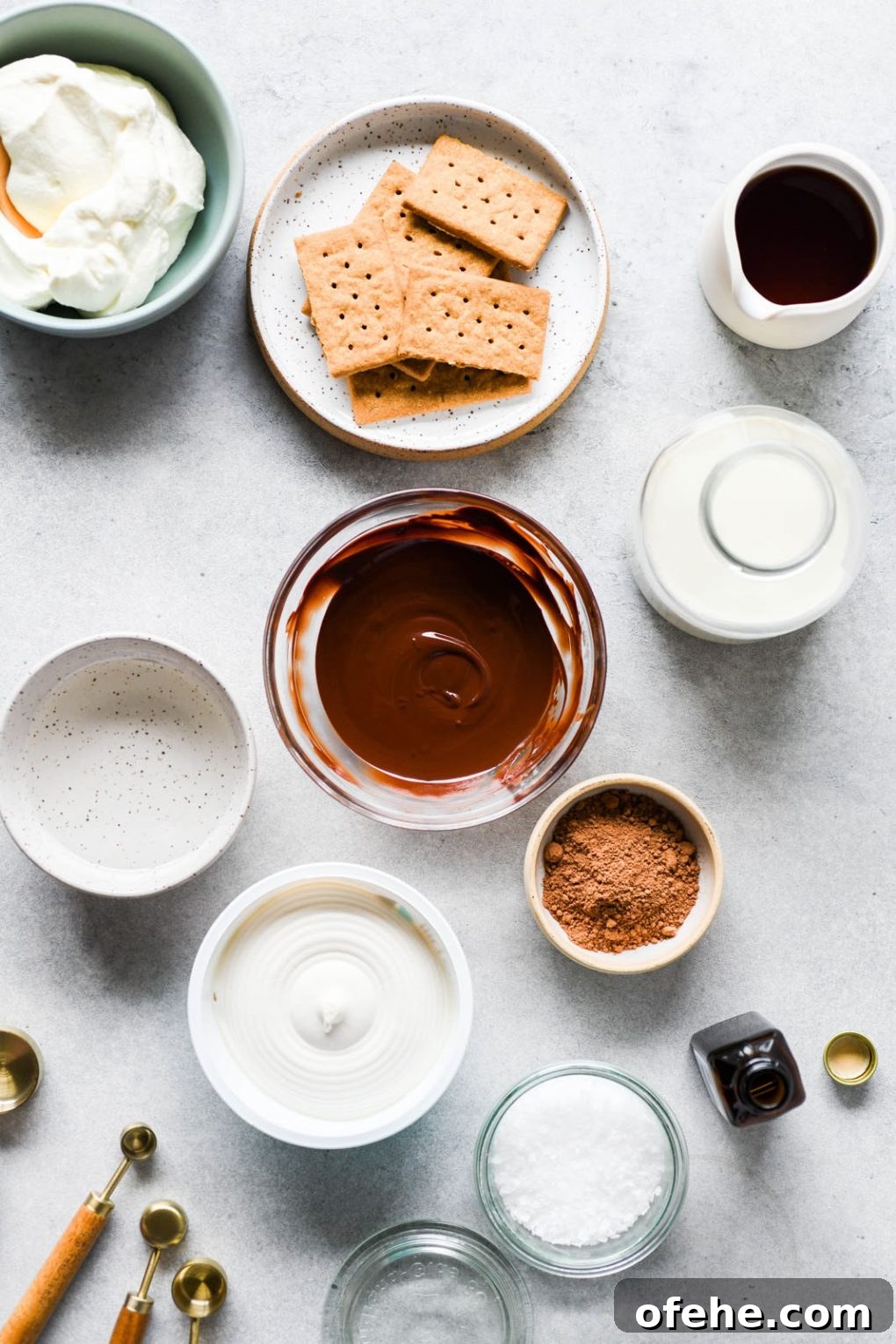 A flat lay of all the ingredients needed to make vegan chocolate mousse. Graham crackers, melted chocolate, non dairy milk, cacao powder, dairy free cream cheese, coconut oil, vanilla, sea salt, and whipped cream.
