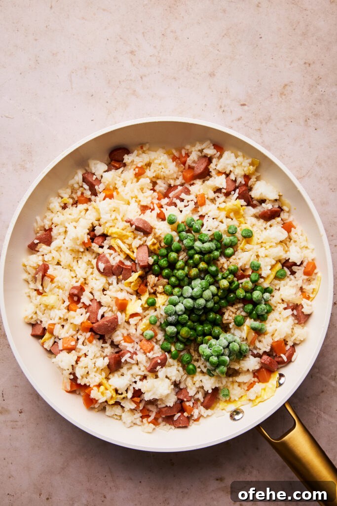Hot Dog Fried Rice Recipe — Quick Weeknight Meal 8 adding frozen peas to the top of hot dog fried rice