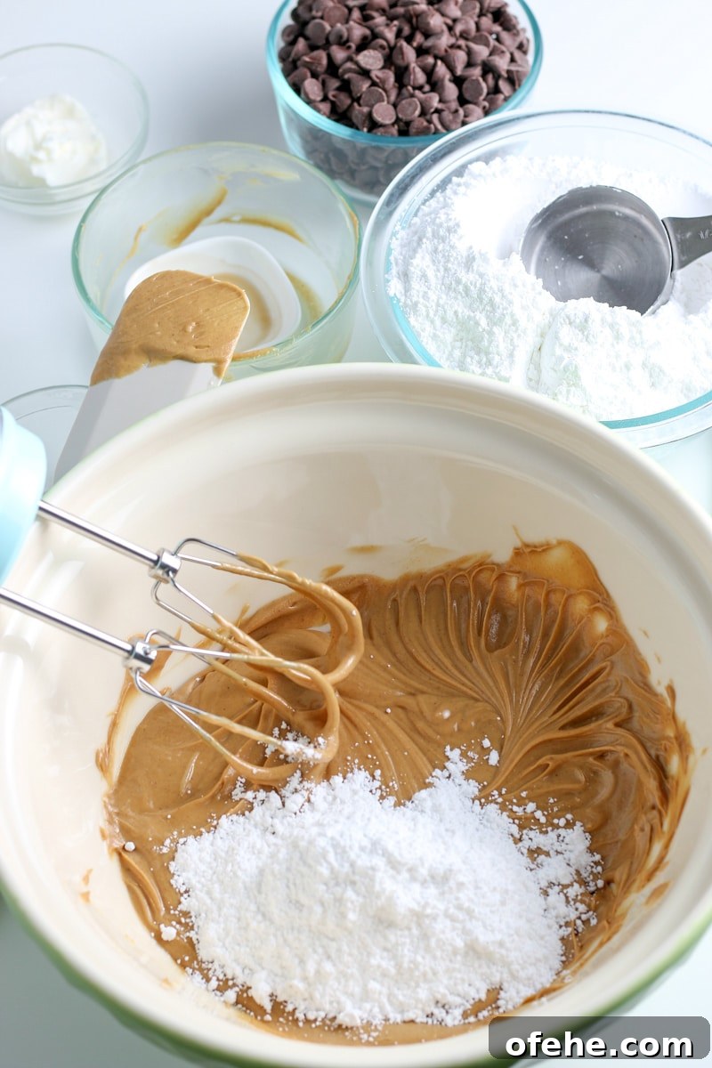 Classic Old-Fashioned Peanut Butter Balls Recipe 5 peanut butter and butter mixture with powdered sugar in a white mixing bowl.