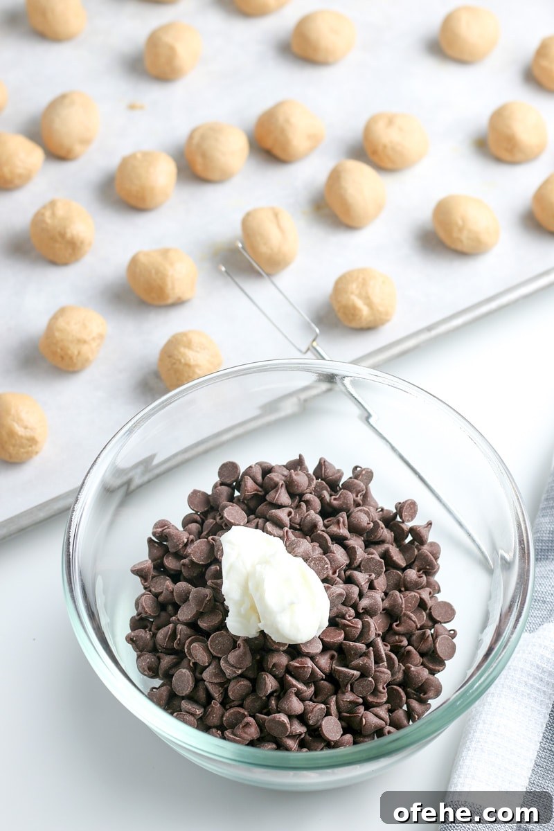 Classic Old-Fashioned Peanut Butter Balls Recipe 7 chocolate chips and vegetable oil in a small glass bowl and peanut butter balls on a baking sheet with parchment paper.