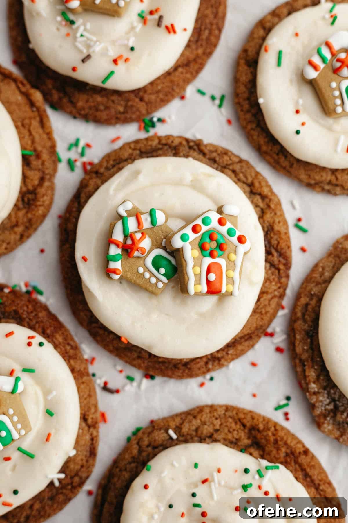 Soft Frosted Gingerbread Cookies with Cream Cheese Frosting Recipe 2 A close up of a gingerbread cookie frosted with cream cheese frosting and a small gingerbread house decoration.
