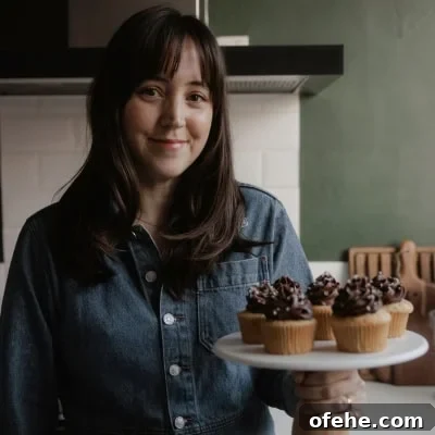 Soft Frosted Gingerbread Cookies with Cream Cheese Frosting Recipe 14 Ella from Alpine Ella is holding a cake stand with cupcakes on it.