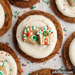 Soft Frosted Gingerbread Cookies with Cream Cheese Frosting Recipe 15 A close up of a gingerbread cookie frosted with cream cheese frosting and a small gingerbread house decoration.