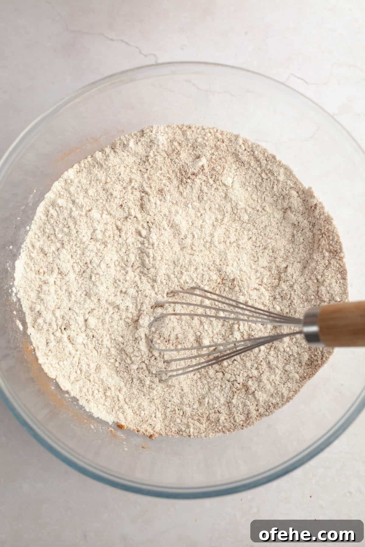 Soft Frosted Gingerbread Cookies with Cream Cheese Frosting Recipe 5 A large glass bowl with flour and spices with a whisk.