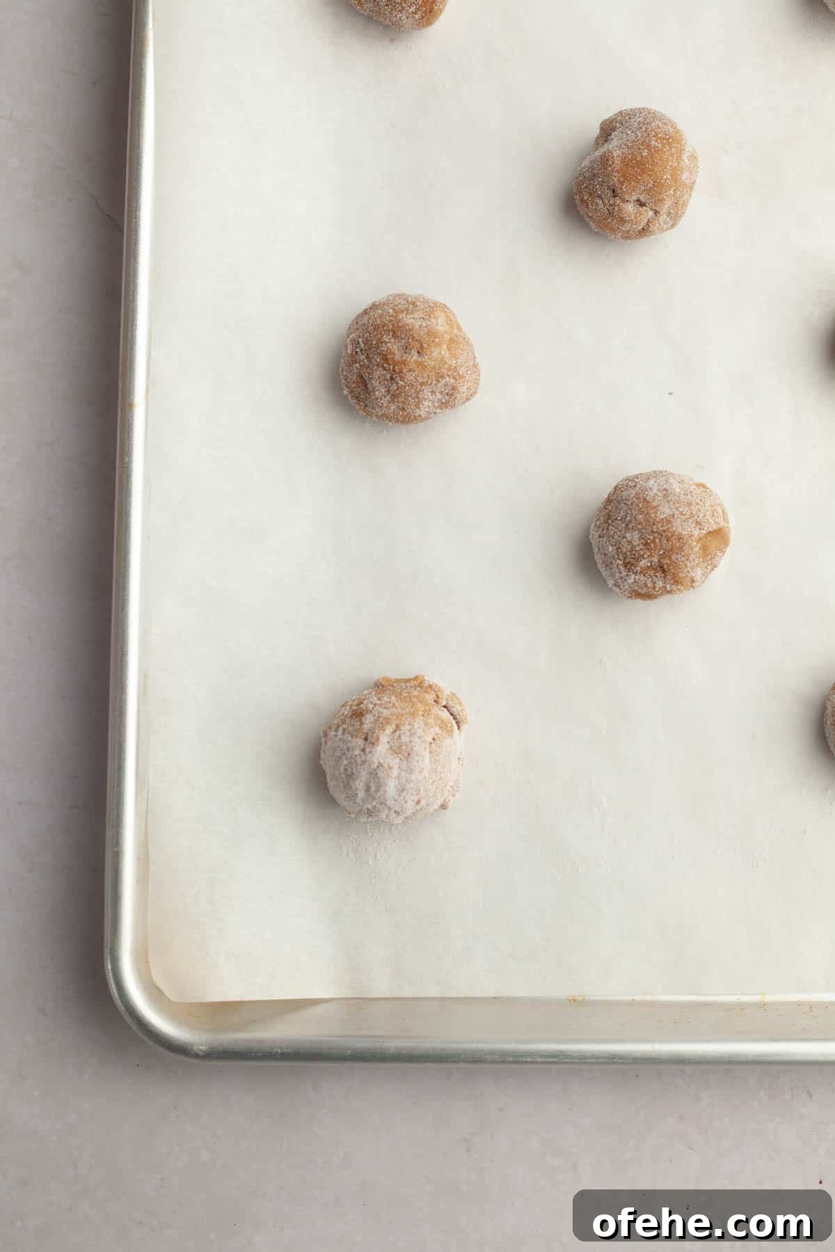 Soft Frosted Gingerbread Cookies with Cream Cheese Frosting Recipe 9 Unbaked gingerbread cookie dough balls on parchment paper on a baking sheet.